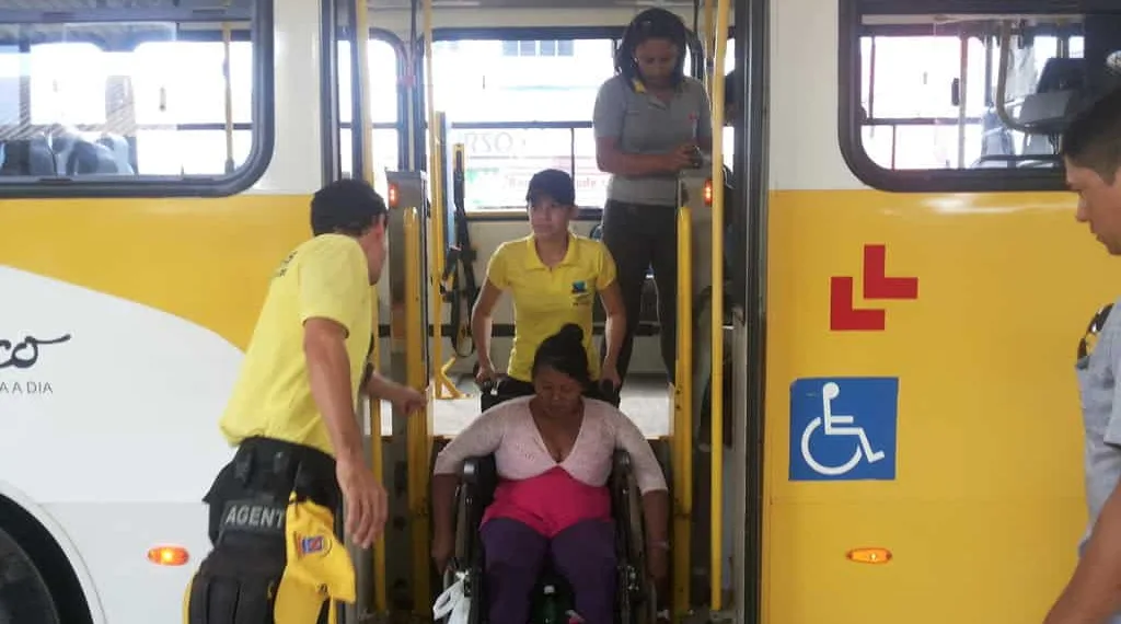 Cadeirante é auxiliada por agentes, na descida de ônibus