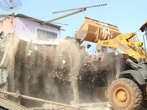 Trator remove escombros após residência ser demolida