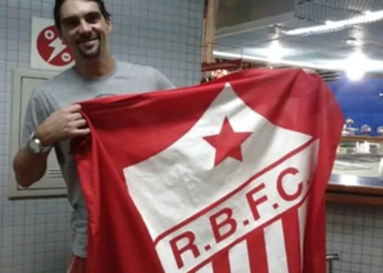 No aeroporto de Rio Branco, o ex-jogador de vôlei Giba tira foto com a bandeira do Rio Branco