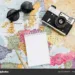 Travel notes mock up. World map, camera, sunglasses and notebook. Flat lay, top view.