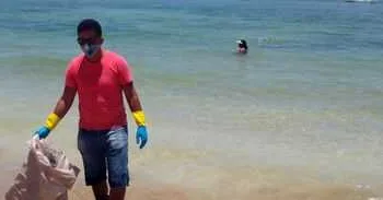 O voluntário Robério Nunes ajuda no trabalho de retirada de óleo de praia em Morro de São Paulo, na Bahia