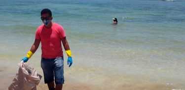 O voluntário Robério Nunes ajuda no trabalho de retirada de óleo de praia em Morro de São Paulo, na Bahia