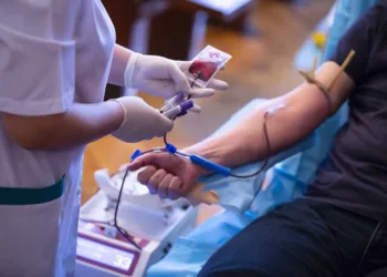 The hand of a man who donates blood. Male donor gives blood in a mobile blood donation center. Blood samples. Hands of the nurse with protective gloves.