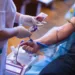 The hand of a man who donates blood. Male donor gives blood in a mobile blood donation center. Blood samples. Hands of the nurse with protective gloves.