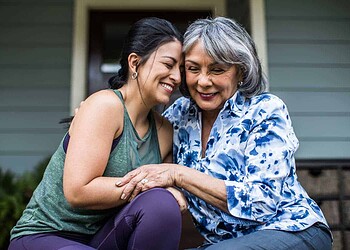 Senior woman and adult daughter laughing on porch