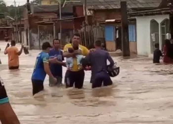 Homem atravessa inundação segurando dois bebês no bairro Ayrton Sena; veja o vídeo