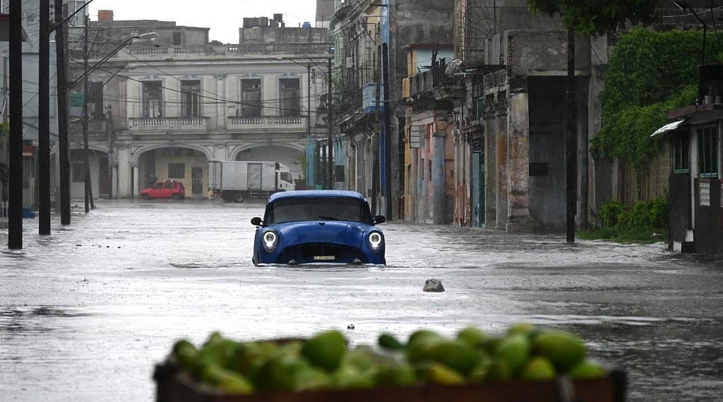 An old American car drives through a flooded street in Havana, on Augusto 29, 2023, during the passage of tropical storm Idalia. Tropical Storm Idalia strengthened into a hurricane this Tuesday and forecasters are forecasting it to become "extremely dangerous" before making landfall on Wednesday in Florida, US. (Photo by Yamil LAGE / AFP)