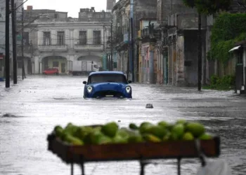 An old American car drives through a flooded street in Havana, on Augusto 29, 2023, during the passage of tropical storm Idalia. Tropical Storm Idalia strengthened into a hurricane this Tuesday and forecasters are forecasting it to become "extremely dangerous" before making landfall on Wednesday in Florida, US. (Photo by Yamil LAGE / AFP)