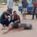 Mulher morre após colisão entre moto e caminhão; marido chora ao lado do corpo