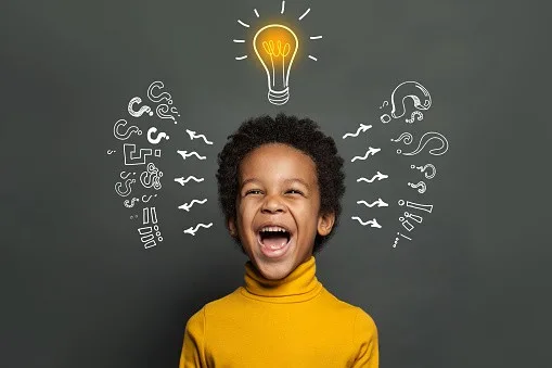 Ideas and brainstorm concept. Happy child school student with lightbulb and chalk question marks