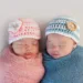 Five week old sleeping boy and girl fraternal twin newborn babies. They are wearing crocheted pink and blue striped hats.