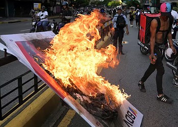 Manifestantes queimam banner durante protesto em Caracas, no dia 30 de julho de 2024, um dia após a eleição presidencial na Venezuela — Foto: Yuri Cortez/AFP