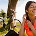 portrait of smiling beautiful woman doing sports in morning in park nature on mat wearing colorful fitness outfit, happy healthy lifestyle, music in earphones, bicycle on background