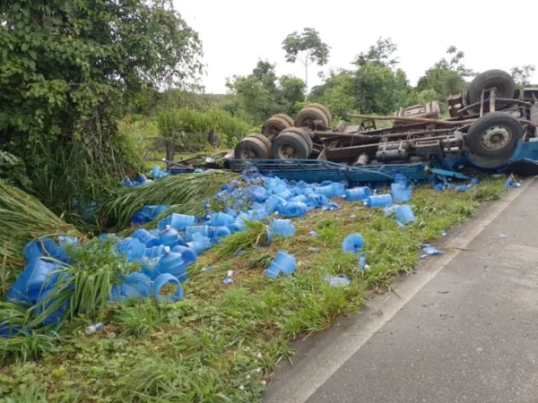 Motorista é resgatado após caminhão com galões de água capotar na BR-364