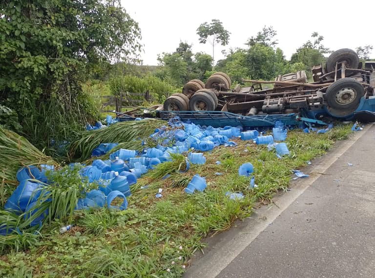 Motorista é resgatado após caminhão com galões de água capotar na BR-364
