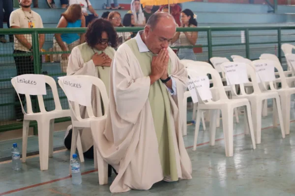 De bata, Bocalom se ajoelha e reza durante o 'Rio de Água Viva' da Diocese de Rio Branco