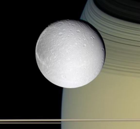 Dione, uma das agora 274 luas de Saturno, vista com Saturno e seus anéis ao fundo: novas descobertas consolidam o lugar de Saturno como o vencedor da competição de número luas no Sistema Solar, com mais luas confirmadas do que todos os outros planetas juntos. — Foto: NASA / JPL / Space Science Institute