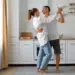 Quer durar no amor? Psicólogo revela 5 segredos que mantêm casais felizes por décadas 8 Casal dança feliz na cozinha — Foto: Freepik