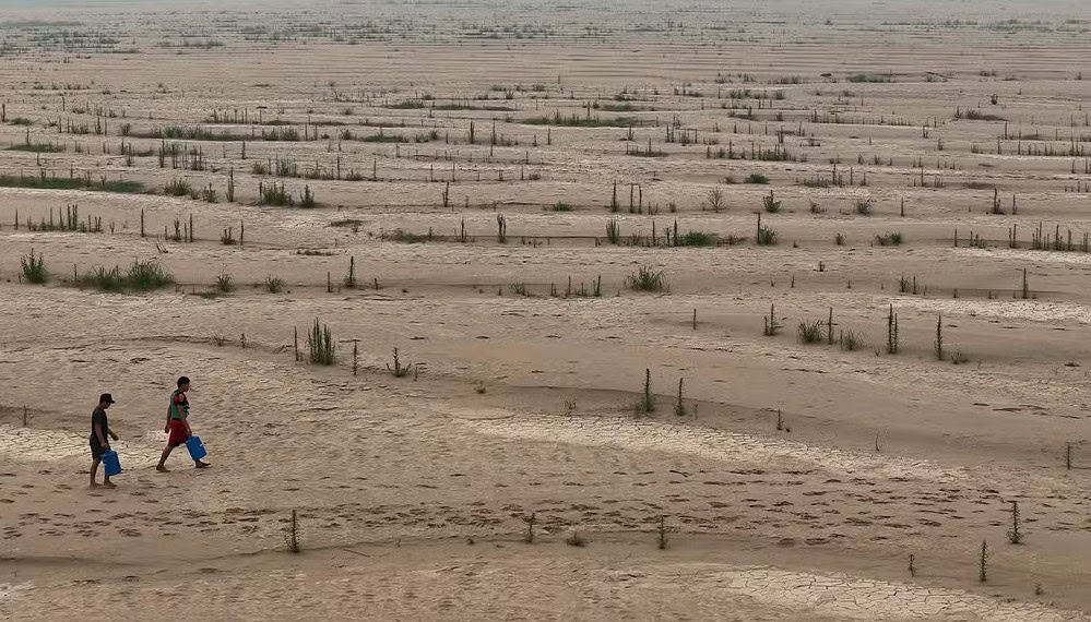 Ribeirinhos carregam galões de água enquanto atravessam bancos de areia do rio Madeira até a comunidade Paraizinho, em meio à pior seca da história. Humaitá, Amazonas. — Foto: Bruno Kelly/Reuters