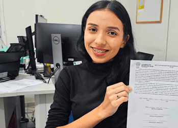 Hillary apresenta o termo de compromisso assinado, documento que a legitima como bolsista não docente do Ieptec. Foto: Ascom/Ieptec.